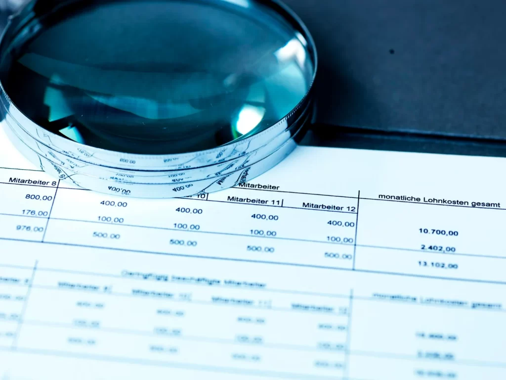 Lupa sobre extrato bancário representando a importância da conciliação bancária.